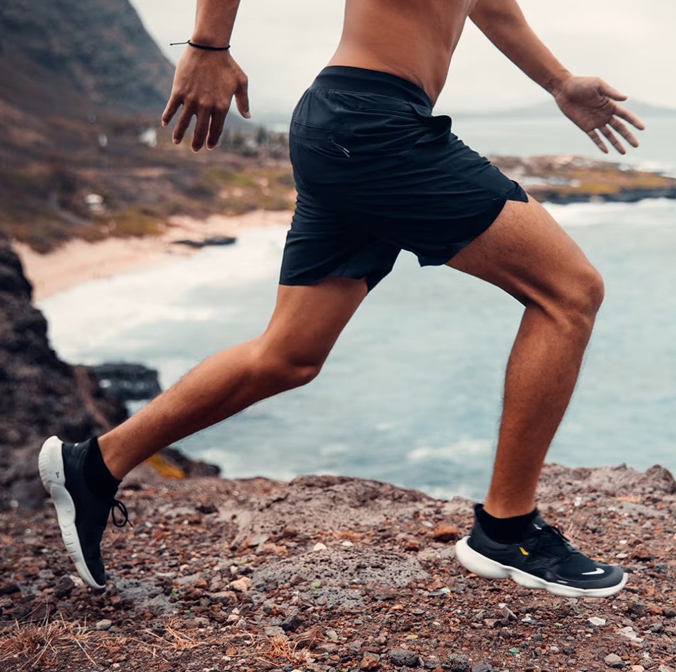 Athlete mid-stride in Ten Thousand Set Short on coastal terrain, highlighting hybrid performance for land and water workouts.